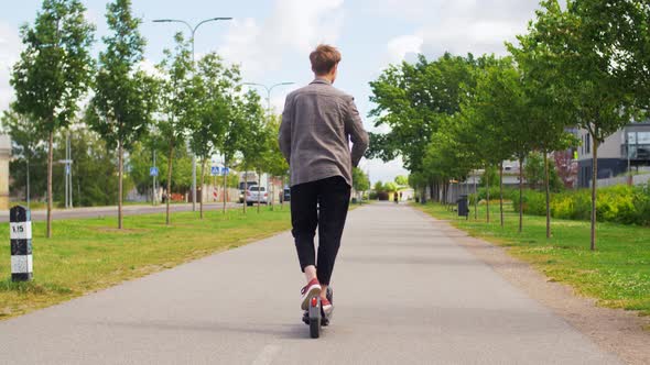 Young Man Riding Electric Scooter on City Street