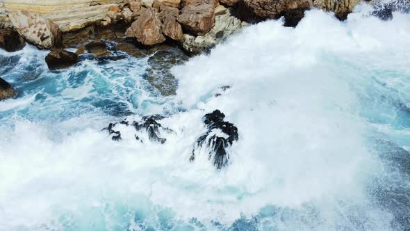 Sea Washes the Rocky Shore Above Aerial Shot Flying Over Coastline Cliffside with Blue Pure Water