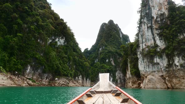 View From Wood Longtail Boat on Lake Near Limestone Cliff and Tropical Forest