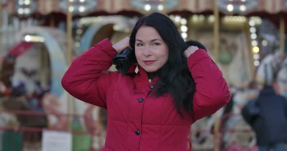 Portrait of Adult Caucasian Woman in Red Coat Putting on Hood, Positive Adult Lady Standing on City