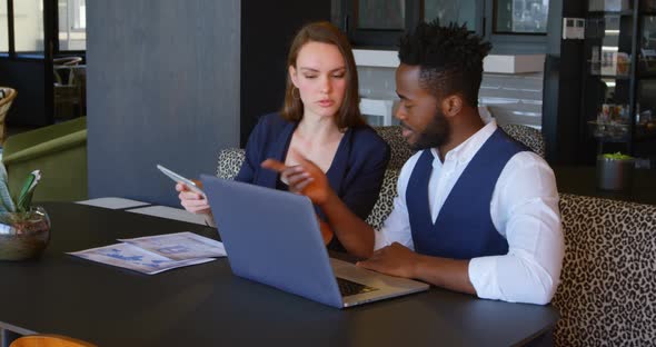 Front view of young cool mixed-race business team planning and sitting at table of modern office 4k