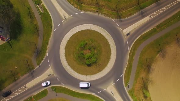Topshot aerial  drone footage of a roundabout with four roads direction traffic.