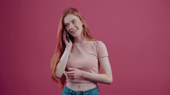 Happy Redhaired Young Woman Talking on the Phone Excited with Her Mouth to Her Mouth