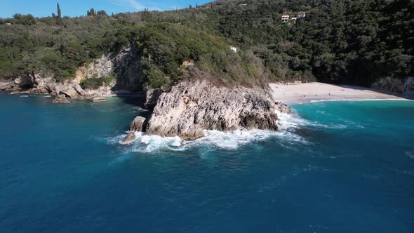 Clockwise rotating droneshot of blue lagoon with white sand and rocky coastline. Clear water breakin