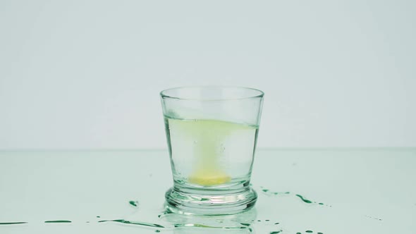 Glass with An Effervescent Tablet Dissolves Slow-motion Shot of Aspirin on a Colored Background 120