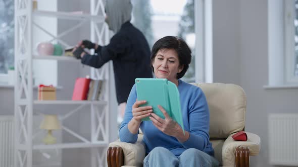 Engrossed Device Addicted Woman Sitting at Home Using Social Media on Tablet As Robber Stealing at