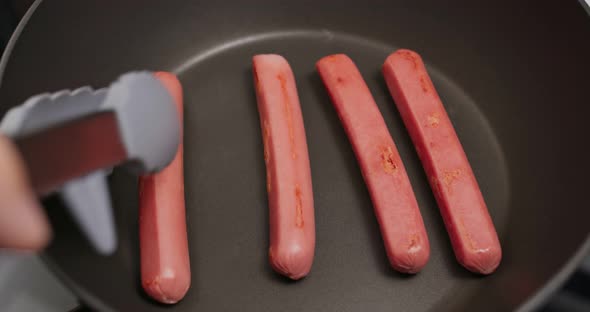 Cooking sausages on the fry pan in kitchen for breakfast