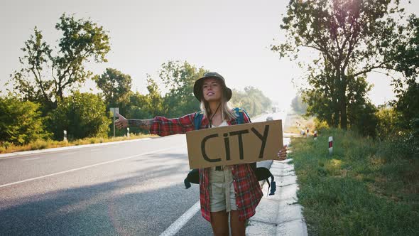 Tourist Young Woman Hitchhiking with Sign City at Highway