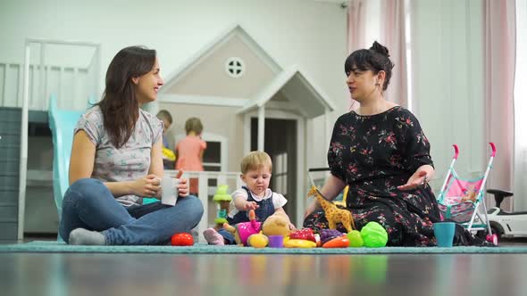 Female Friends Chatting While Their Kids Playing