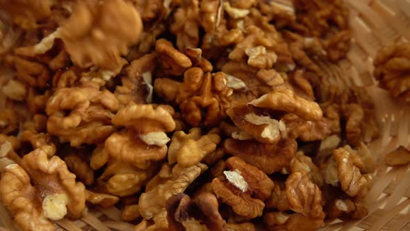 Walnut kernels fall into a wicker basket. Slow motion.