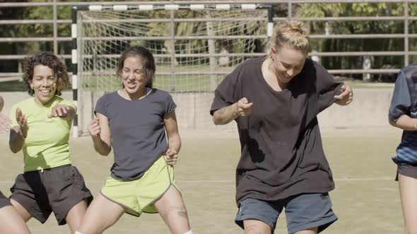 Front View of Happy Female Football Players Dancing at Stadium