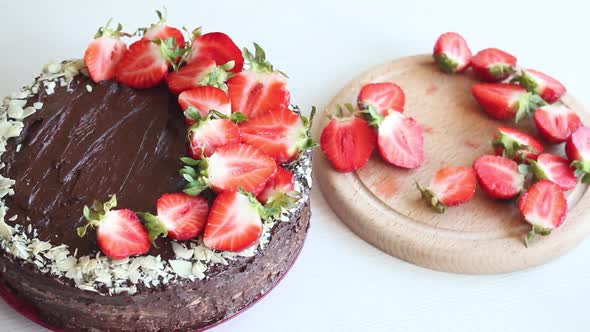 A Woman Decorates A Cake With Strawberries.