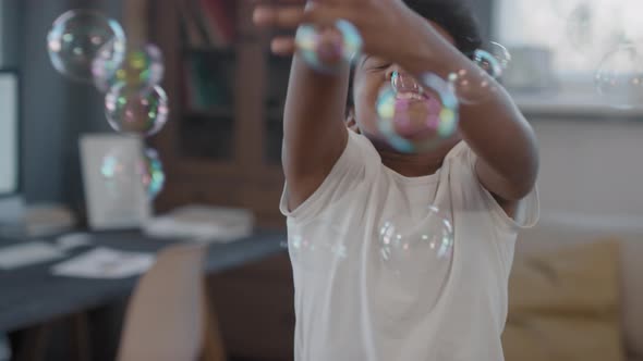 Happy Mixed-Race Kid Catching Soap Bubbles alt