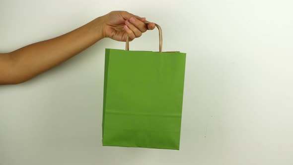 A woman holds a green shopping bag in honor of Black Friday and Cyber Monday.