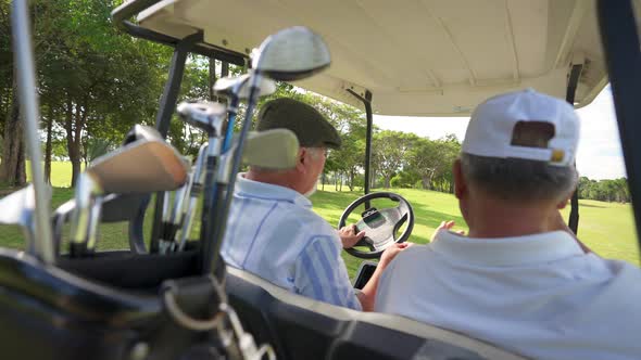 4K Asian senior man friends driving golf cart on golf course in summer sunny day