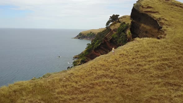 Girl Walking Along Steep Coastal Cliff