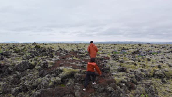 Drone Of Hiking Couple Over Mossy Iceland Landscape