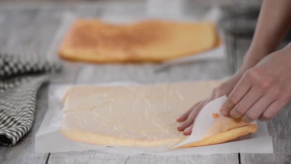 Female Hands Peeling the Parchment Paper From the Bottom of the Sponge Cake