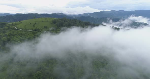 Aerial View of Dense White Mist Covering Green Hills and Mountain Tops