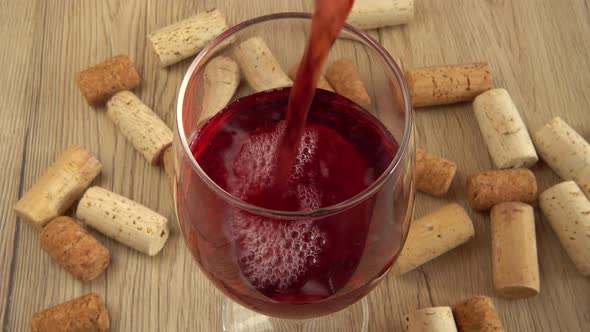 Wine is poured into a glass on the background of wine corks.	