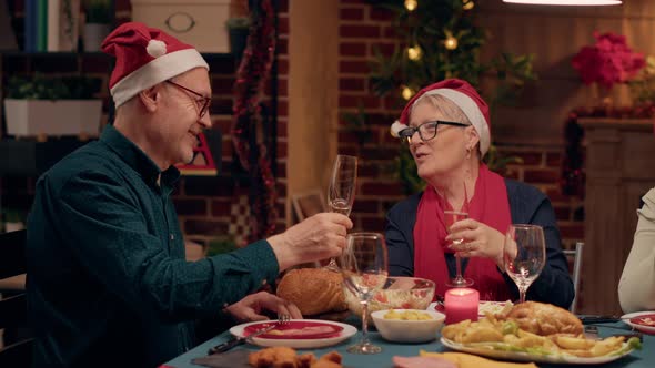 Festive Senior Couple Talking to Each Other While Drinking Champagne and Celebrating Winter Holiday