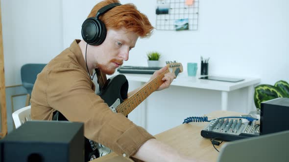 Slow Motion of Ambitious Musician Playing Electric Guitar and Using Computer Indoors at Home