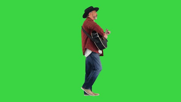 Man in a Cowboy Hat Walking and Playing Guitar on a Green Screen Chroma Key