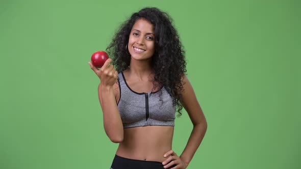 Young Beautiful Hispanic Woman with Gym Clothes Holding Apple