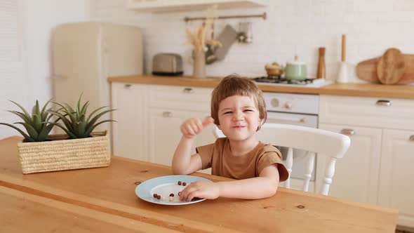 a Little Caucasian Boy Eats Krunchy Breakfast and Enjoys It at Kitchen Table