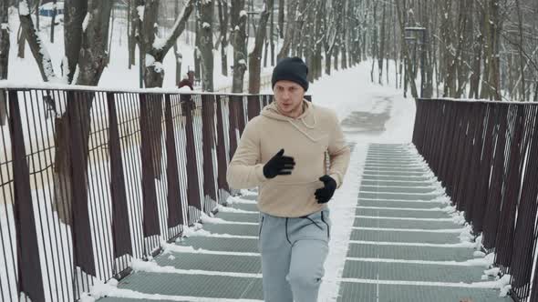 Fit Man Jogging on Metal Bridge in Winter