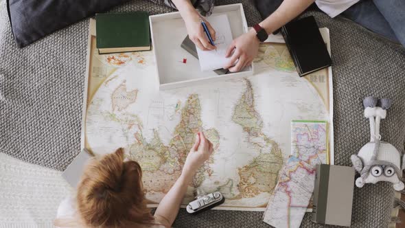 Young Couple Girl and Guy Are Planning Travelling Route Laying in Bed and Pointing Places for Visit