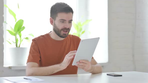 Successful Young Man Celebrating on Tablet in Office