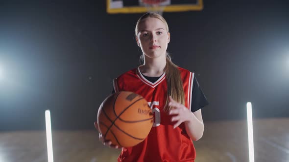 Portrait of a Cheerful Female Basketball Player Holding a Ball in Her Hands and Looking at the