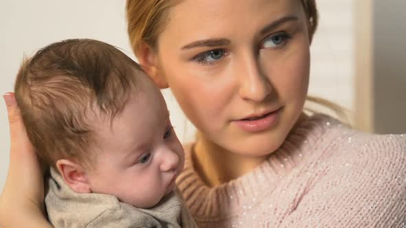 Attractive Young Female Holding Little Adorable Baby and Talking to Him, Care