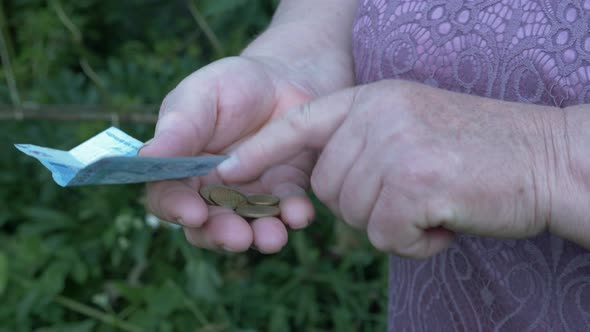 Mature older female counts money in her wallet. Old retired woman counting coins in hands. 