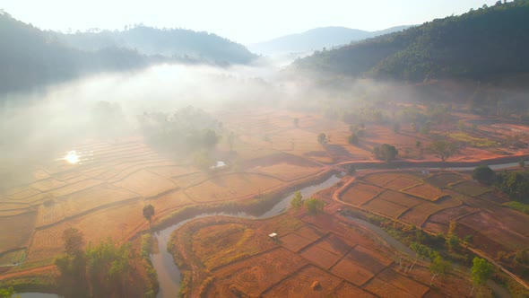 Aerial view over villages and barren fields in countryside during sunrise