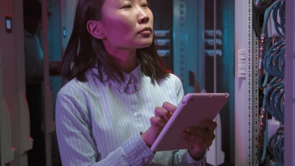 Female Data Center Technician Checking Computing Equipment