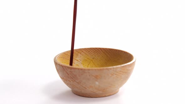 Pouring soy sauce into bowl on white background