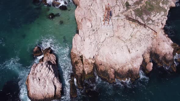 Aerial Top View of Waves Break on Rocks in a Blue Ocean