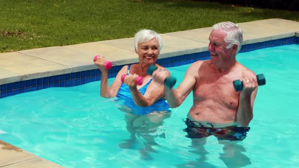 Senior couple exercising with dumbbells in the pool
