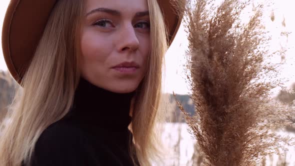 Millennial Woman European Blonde Woman Smiling with Beige Hat in Black Sweater in the Countryside