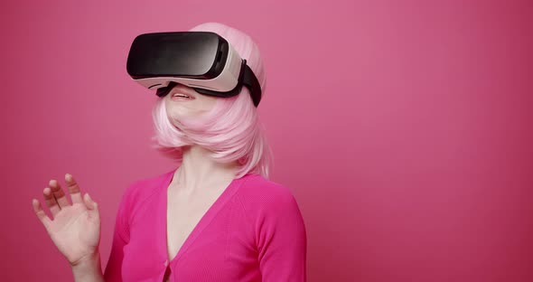 Woman Uses a Virtual Reality Glasses on Isolated Pink Background