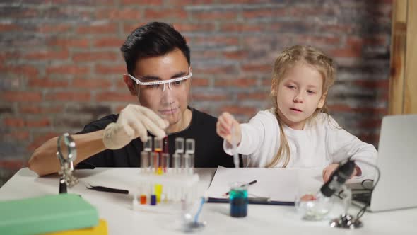 Asian Teacher Supports Girl Dropping Reagent Into Beaker