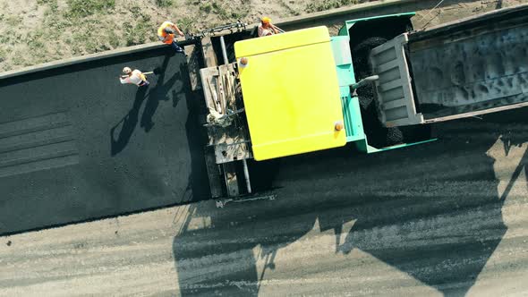 Asphalt Road in Progress with Workers in a Top View. Road Construction Process