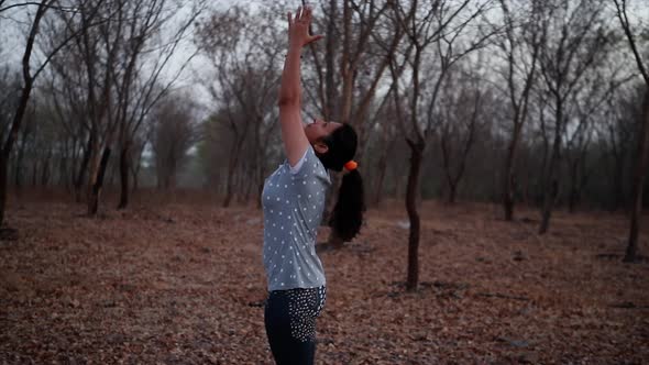 young woman doing yoga in a park near a river during the morning, lens flare and beautiful view back