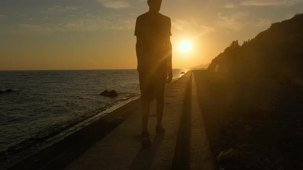 Man Walks Along the Seashore at Sunset, the Concept of Travel and Relaxation.