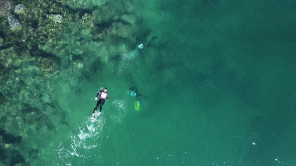 Unique view of a single person snorkeling above a group of scuba divers below the water in the ocean