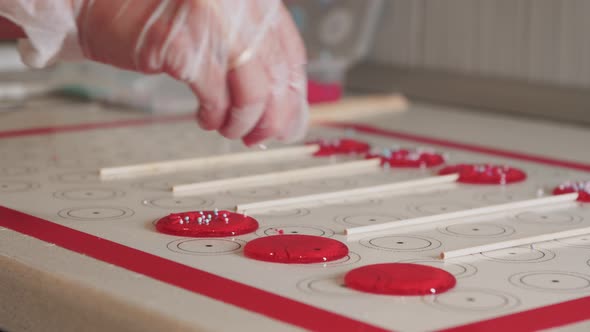 Making Lollipops  Pouring Sprinkling on Top of Red Caramel on the Paper