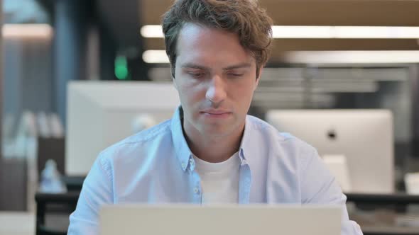 Close Up of Man Smiling at Camera While Using Laptop