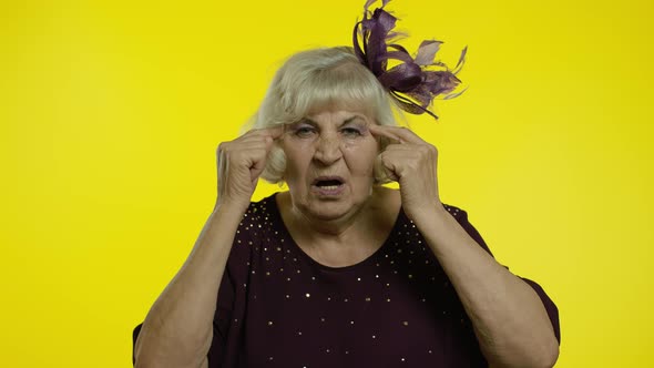 Displeased Annoyed Senior Old Woman Showing Stupid Gesture, Elderly Grandma on Yellow Background